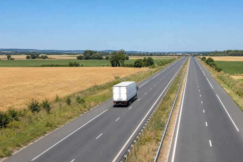 Camion de déménagement sur une route nationale bordée de champs
